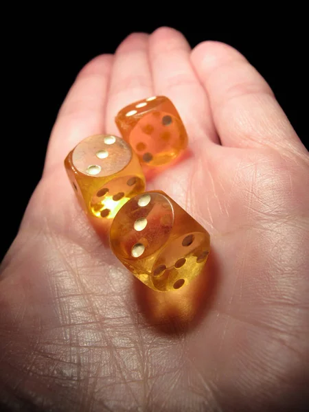 Hand holding three old dice on a black background