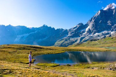 Genç kız dağlarda göl kenarında dans ediyor..