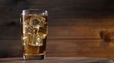 Bir bardak limonata buz küpleri ve kabarcıklar ile. Koyu ahşap arka plan üzerinde. Kaymak vurdu. Döner platformu.