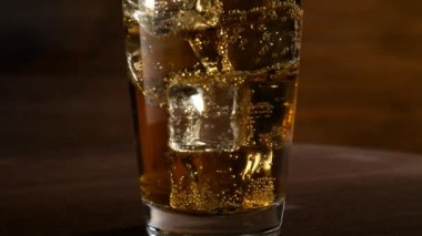 Bir bardak limonata buz küpleri ve kabarcıklar ile. Koyu ahşap arka plan üzerinde. Rotasyon ile.