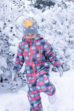 Karlı ormanda koşan küçük bir kız.