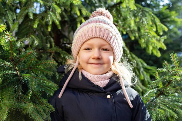 Little beautiful girl with lovely smile posing near fir tree — Stock Photo, Image