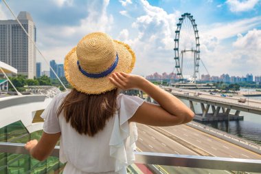 ŞARKI, ŞARKI - 26 Şubat 2020: Singapur Flyer 'a bakan kadın yolcu - güneşli bir günde Singapur' da dev bir dönme dolap