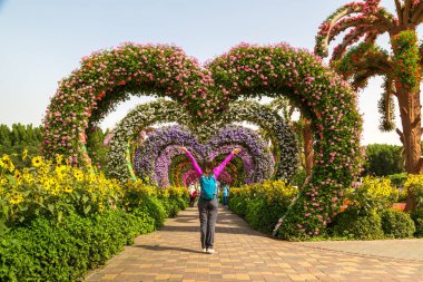 DUBAI, BİRLİK ARAB EMIRATES - 31 Ocak 2020: Dubai 'de güneşli bir günde, Birleşik Arap Emirlikleri' nde turist kadın ve renkli kalp şeklinde çiçek sokağı