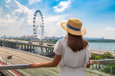 ŞARKI, ŞARKI - 26 Şubat 2020: Singapur Flyer 'a bakan kadın yolcu - güneşli bir günde Singapur' da dev bir dönme dolap