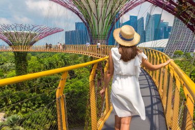 SINGAPORE - 23 Haziran 2019 Singapur Körfezi yakınlarındaki Gardens 'taki Skyway Köprüsü' nde beyaz elbise ve hasır şapka giyen kadın gezgin