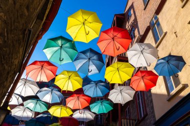 QUEBEC, CANADA - 2 Nisan 2020: Güneşli bir günde eski Quebec şehrinde bir caddenin üzerinde asılı renkli şemsiyeler