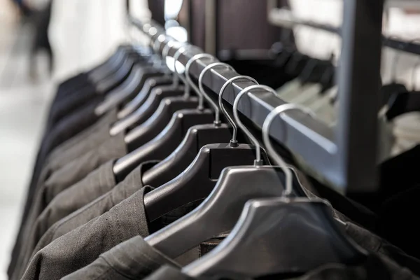 Black clothes on a black hangers — Stock Photo, Image