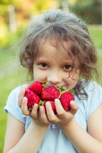 Маленька дівчинка з жменькою полуниці — стокове фото