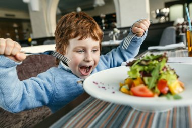 Salata yemek çatal ile kırmızı saçlı çocuk