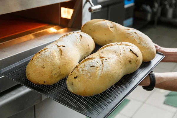 Baker dostaje gorący chleb z pieca — Zdjęcie stockowe