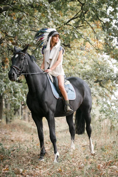 Portret van de jonge vrouw en zwarte paard in een bos. — Stockfoto