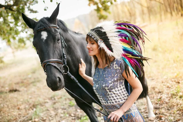 Portret van de jonge vrouw en zwarte paard in een bos. — Stockfoto