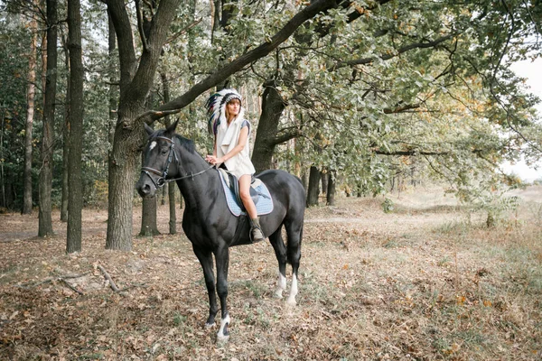 Porträtt av ung kvinna och svart häst i skogen. — Stockfoto