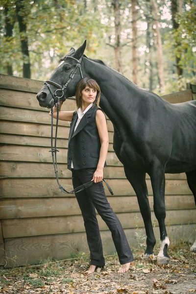 Portret van de jonge vrouw en zwarte paard in een bos. — Stockfoto