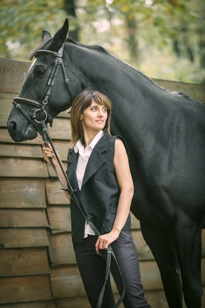 Retrato de mujer joven y caballo negro en un bosque . — Foto de Stock