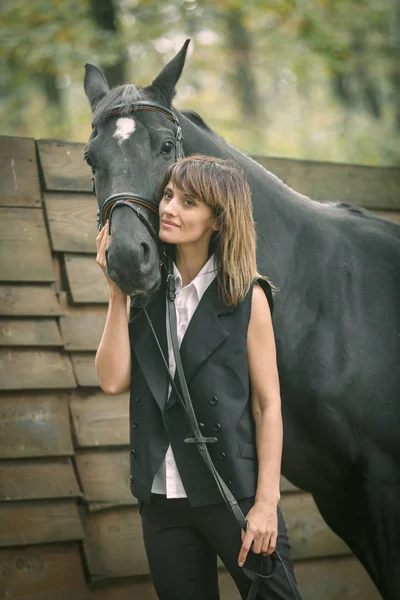 Retrato de mujer joven y caballo negro en un bosque . — Foto de Stock