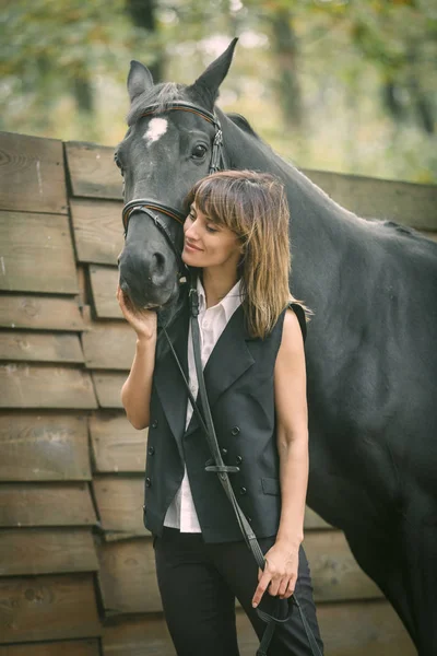 若い女性と森の中の黒い馬の肖像画. — ストック写真