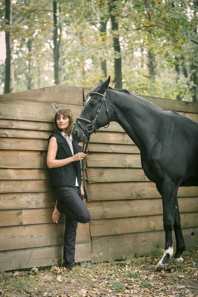 Retrato de mujer joven y caballo negro en un bosque . — Foto de Stock