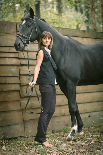 Retrato de mujer joven y caballo negro en un bosque . —  Fotos de Stock