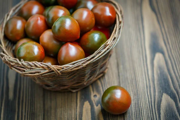 Tomates Kumato em uma tigela de salgueiro trançado — Fotografia de Stock