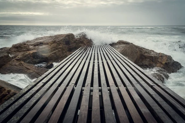 Деревянный пирс в бурном океане — стоковое фото