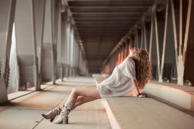 Endüstriyel köprü konumunda poz güzel kıvırcık genç kadın