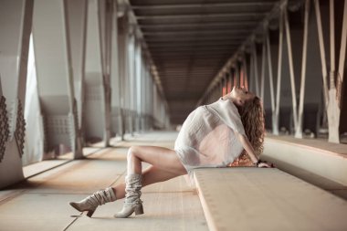 Endüstriyel köprü konumunda poz güzel kıvırcık genç kadın