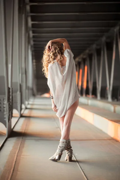 Mooie gekrulde jonge vrouw staande op industriële brug locati — Stockfoto