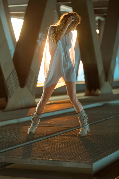 Linda loira encaracolado mulher de pé em locati ponte industrial — Fotografia de Stock