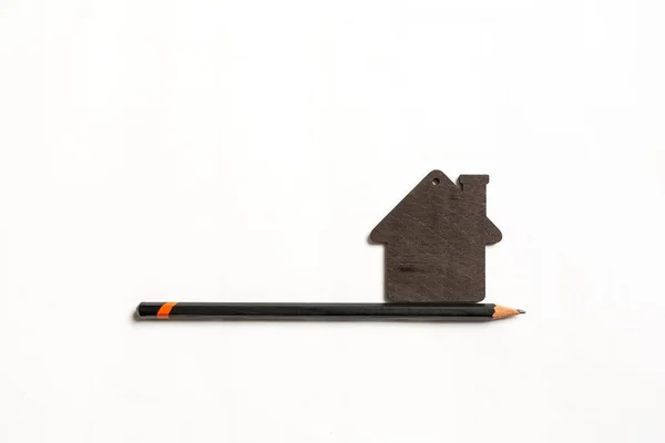 Το μικρό μαύρο μοντέλο ενός σπιτιού με μαύρο μολύβι στο ένα λευκό έκφραση — Φωτογραφία Αρχείου