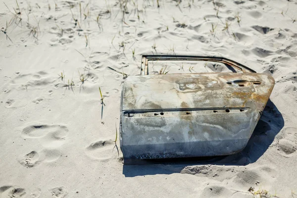 Porte de voiture rouillée laissée comme une poubelle ou un déchet dans une dune de sable — Photo