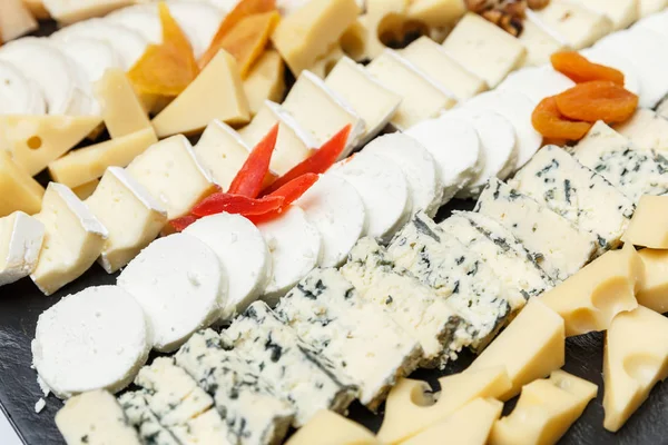 Variety of cheeses sliced on a stone plate — Stock Photo, Image