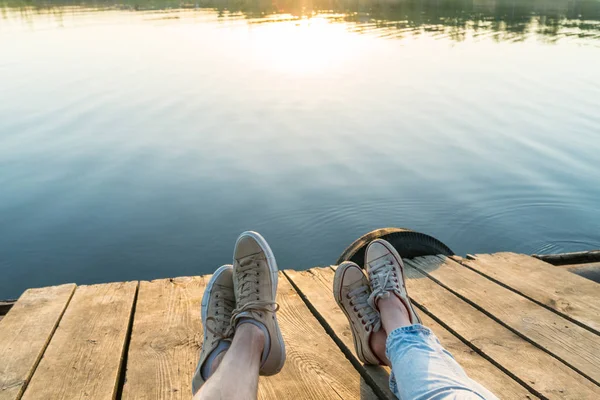 Lifestyle-Ansicht der Beine eines Paares mit Turnschuhen auf einer Holzplatte — Stockfoto