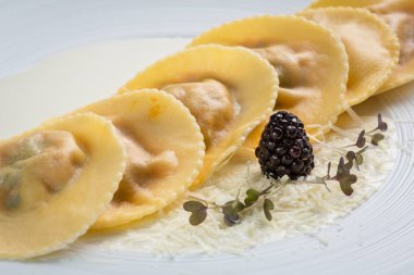 Beyaz tabakta kremalı sosisli Ravioli..