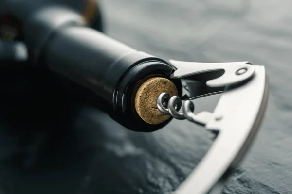 Stainless  wine corkscrew in a cork of wine bottle neck on a bla — Stock Photo, Image