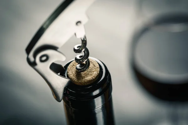 Rostfritt vin korkskruv i en kork av vin flaska hals på en bla — Stockfoto