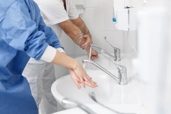 Doctors washing hands using disinfecting liquids in a surgical clinic. Healthcare and medicine concept