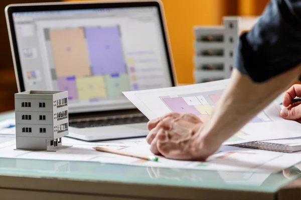 インテリアデザイナーは 設計図とラップトップをテーブルの上に置き スタジオでアパートの計画で働いています 建築設計局作業概念 — ストック写真
