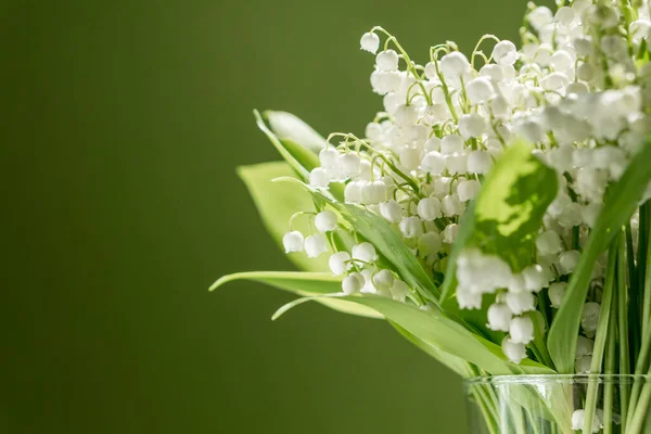 緑の背景にガラスの花瓶に谷のユリの花束 — ストック写真