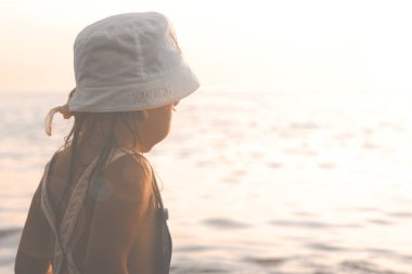 Gün batımında denize bakarak küçük kız 