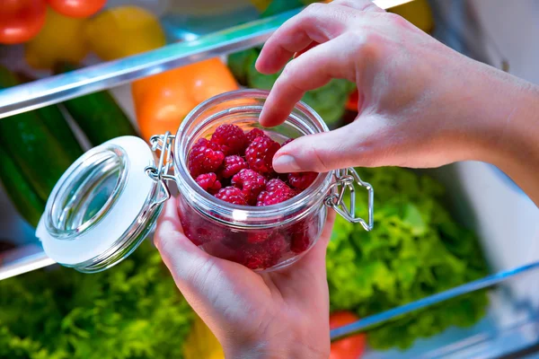 Kvinna tar de färska hallon från öppna kylskåpet — Stockfoto