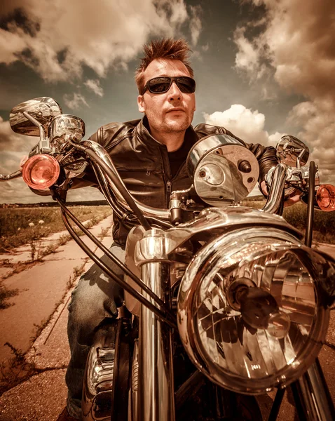 Motociclista en una chaqueta de cuero montando una motocicleta en la carretera —  Fotos de Stock