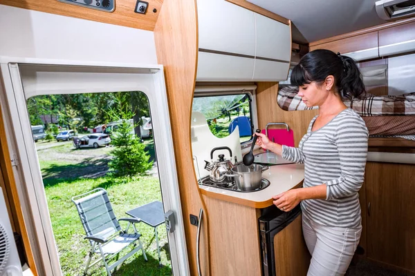 Woman cooking in camper, motorhome interior