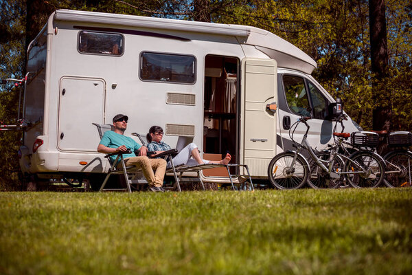 Woman with a man resting near motorhomes in nature. Family vacat