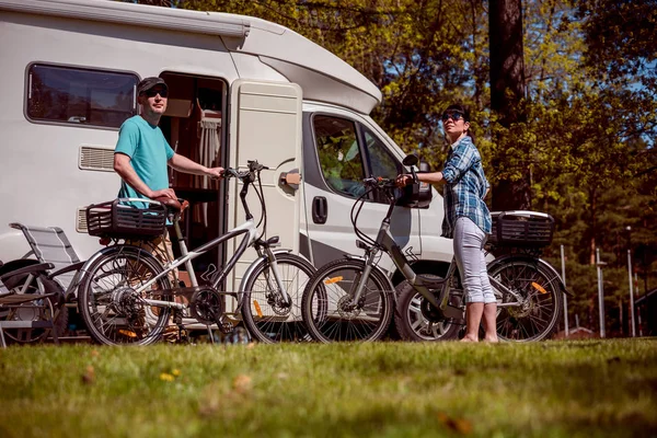 Mulher com um homem em bicicleta elétrica descansando no acampamento . — Fotografia de Stock