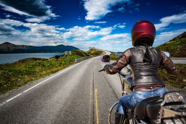 Motorcu kız Norveç Atlantic Ocean Road bir dağ yolu rides. 