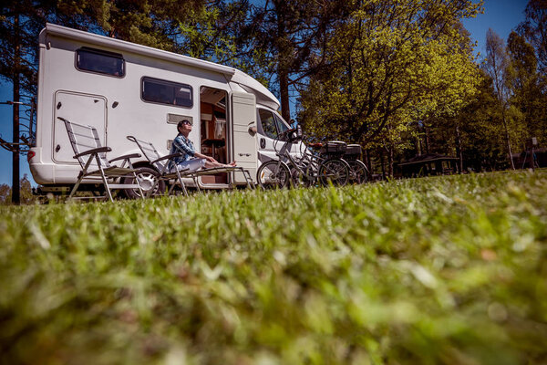 Woman resting near motorhomes in nature. Family vacation travel,