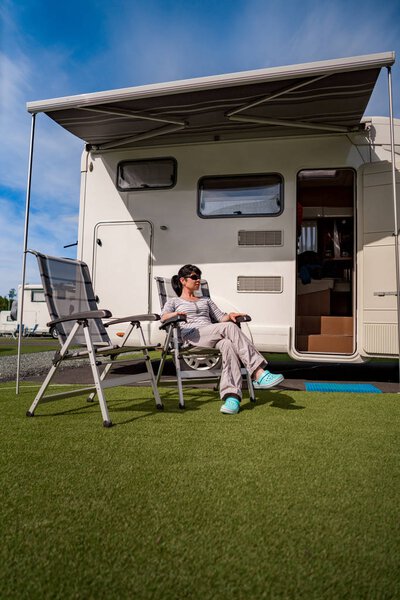 Woman resting near motorhomes in nature. Family vacation travel,