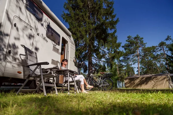 Nainen lepää lähellä matkailuautoja luonnossa. Perhelomamatka , — kuvapankkivalokuva